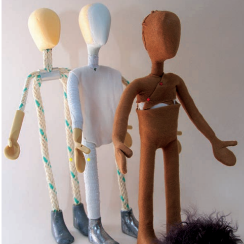 Drei Puppen in verschiedenen Farben und Materialien stehen nebeneinander.