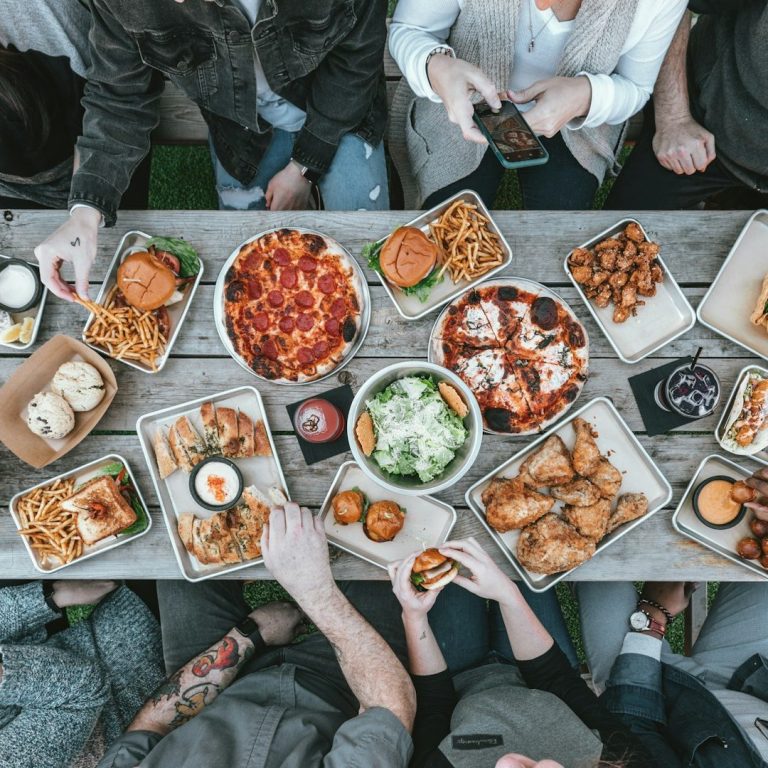 Ein Tisch voller vielfältiger Gerichte, darunter Pizza, Salate und Snacks.